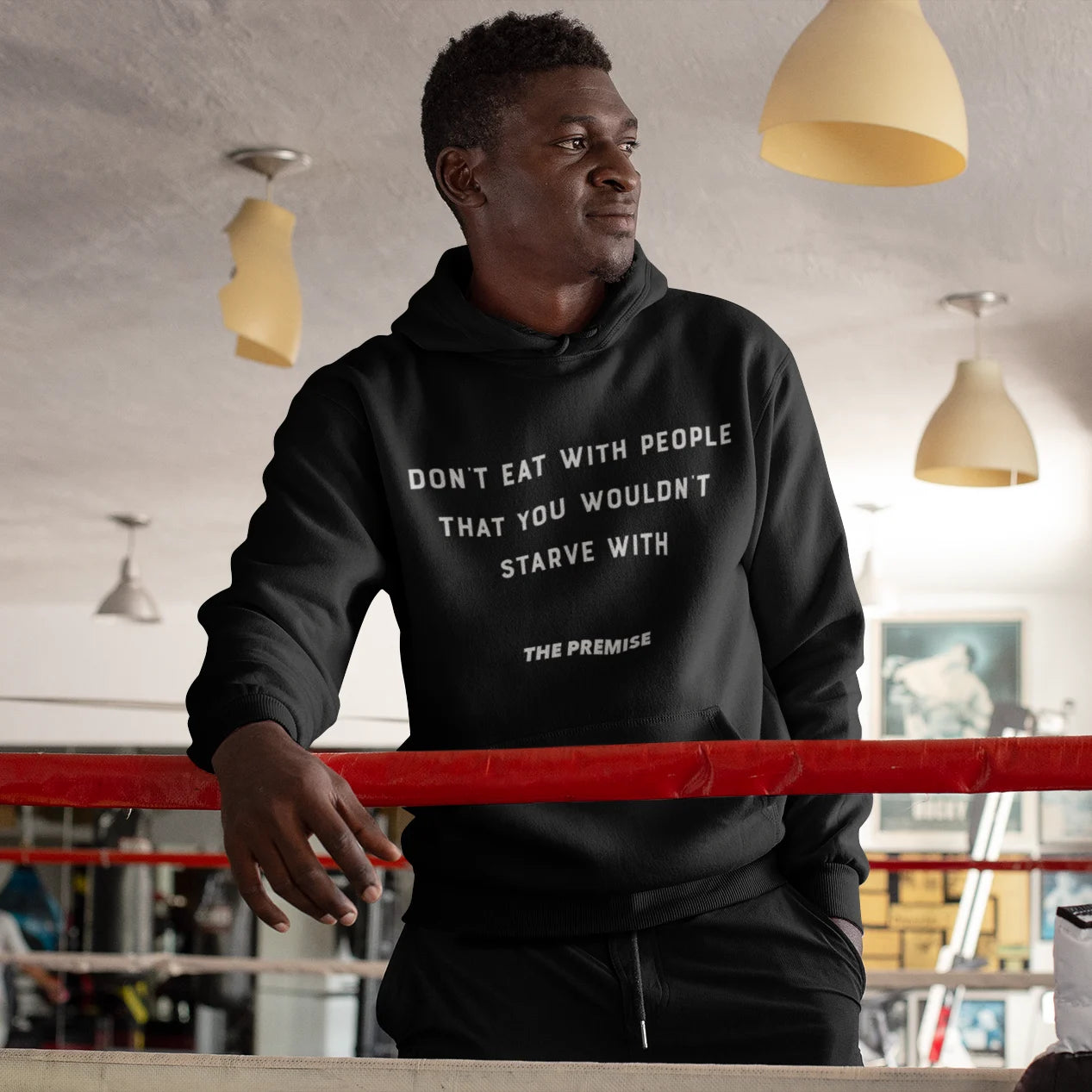 Athlete wearing "Don't Eat with People That You Wouldn't Starve With" hoodie in a boxing gym, symbolizing loyalty and ambition.