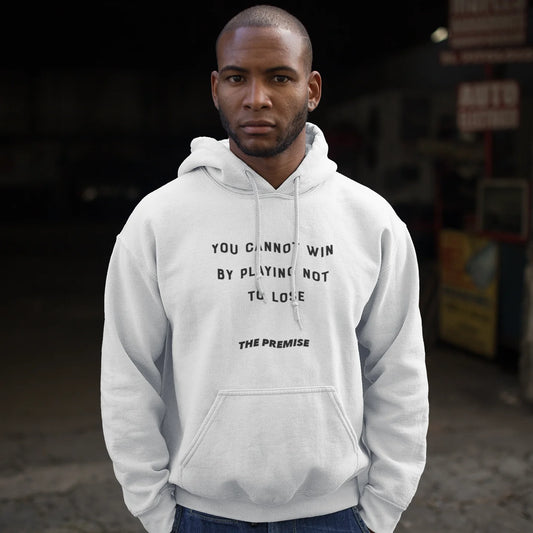 Man in white hoodie with a fearless message about playing to win, standing strong in an urban garage setting.