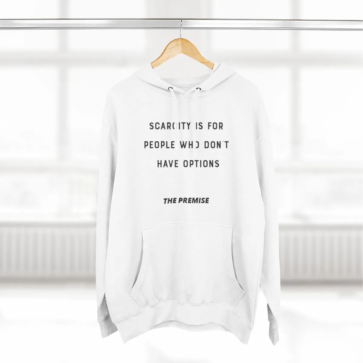 White hoodie with "Scarcity is for people who don’t have options" message, hanging on a hanger, symbolizing a mindset shift towards abundance.