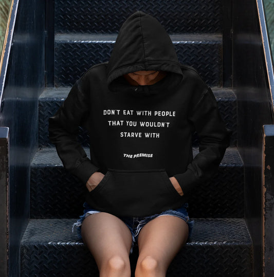 Mysterious and powerful shot of a woman in a black hoodie sitting on urban steps, embodying resilience and ambition.